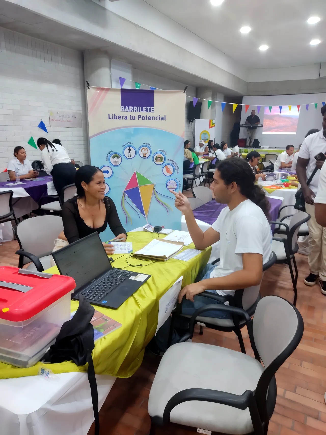 Una profesional atiende a un joven en la mesa de Barrilete, con el pendón «Libera tu potencial» detrás