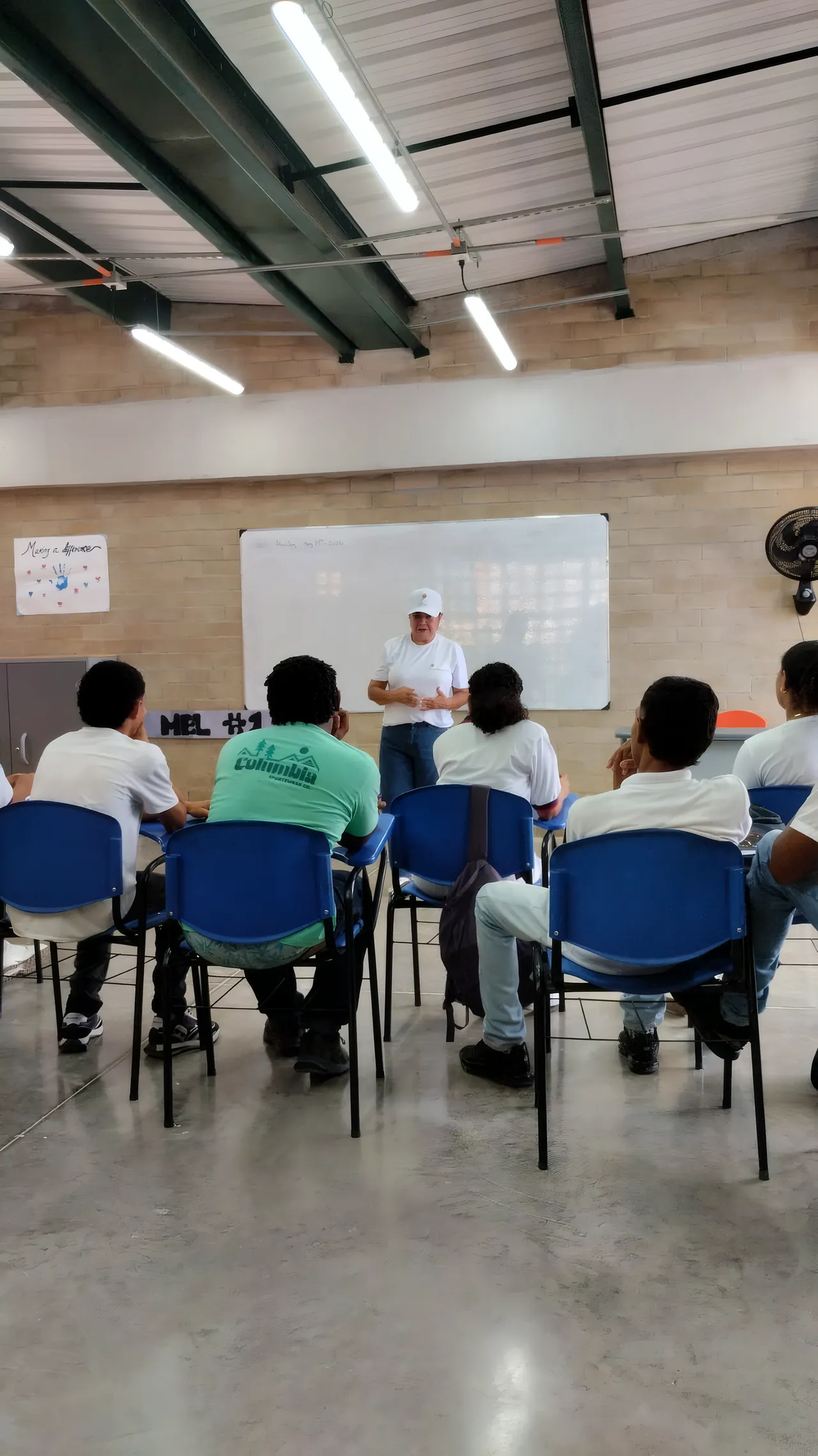 Estudiantes sentados en un aula frente a un facilitador y un tablero