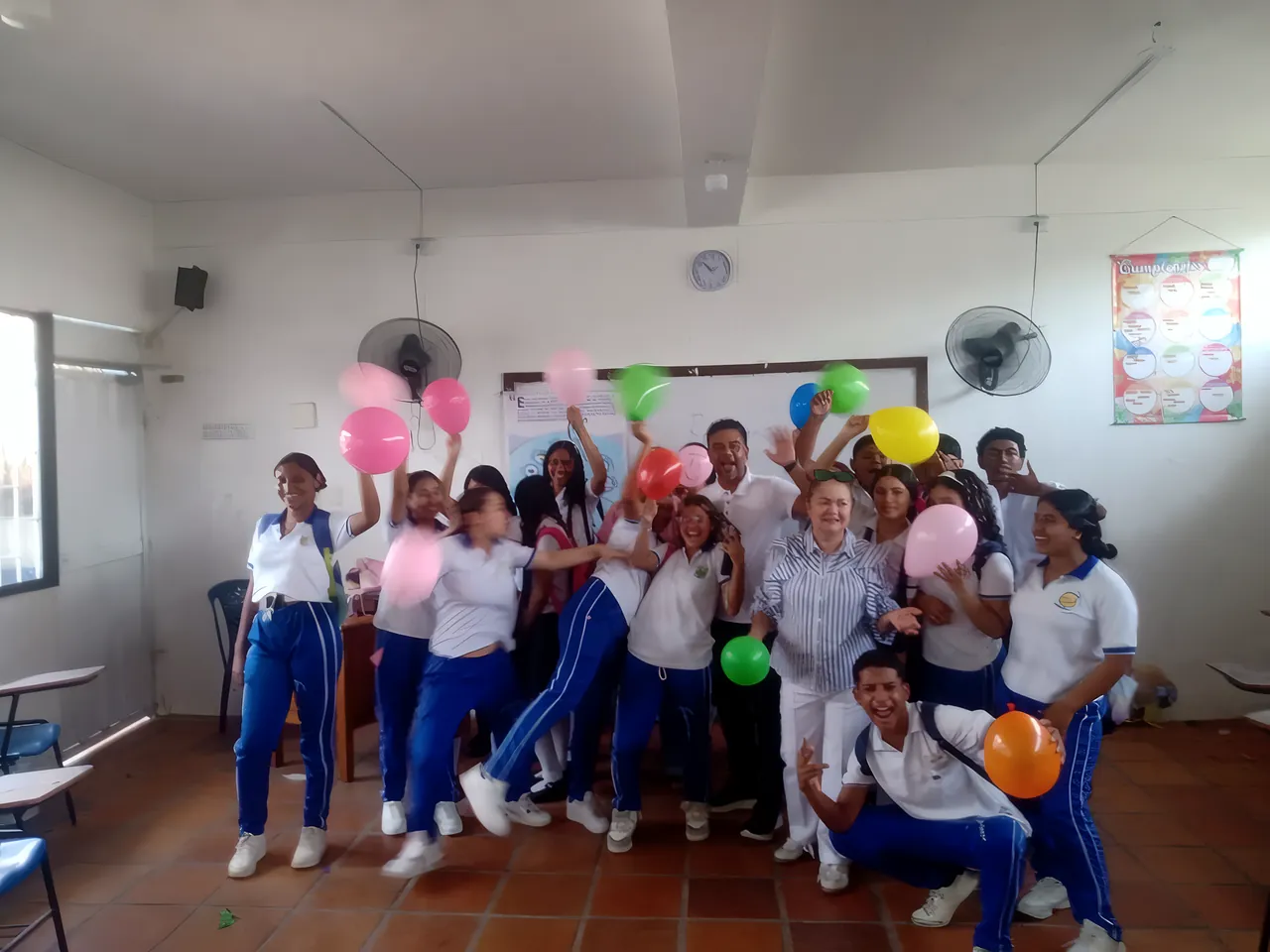 Estudiantes de uniforme celebran con globos de colores al final de un taller
