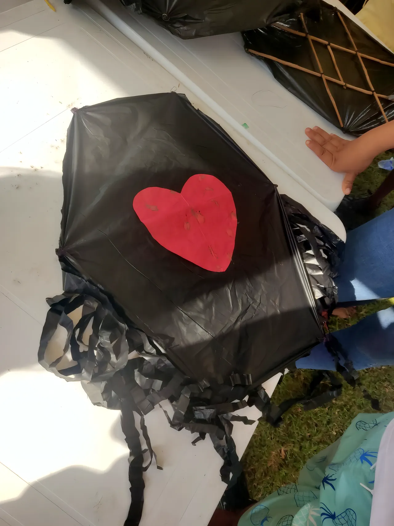 Un barrilete de plástico negro con un corazón rojo de papel en el centro