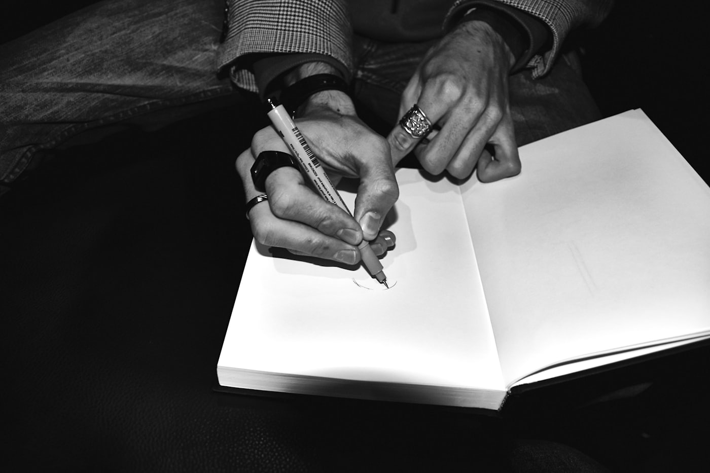 Manos escribiendo en un cuaderno abierto con un bolígrafo