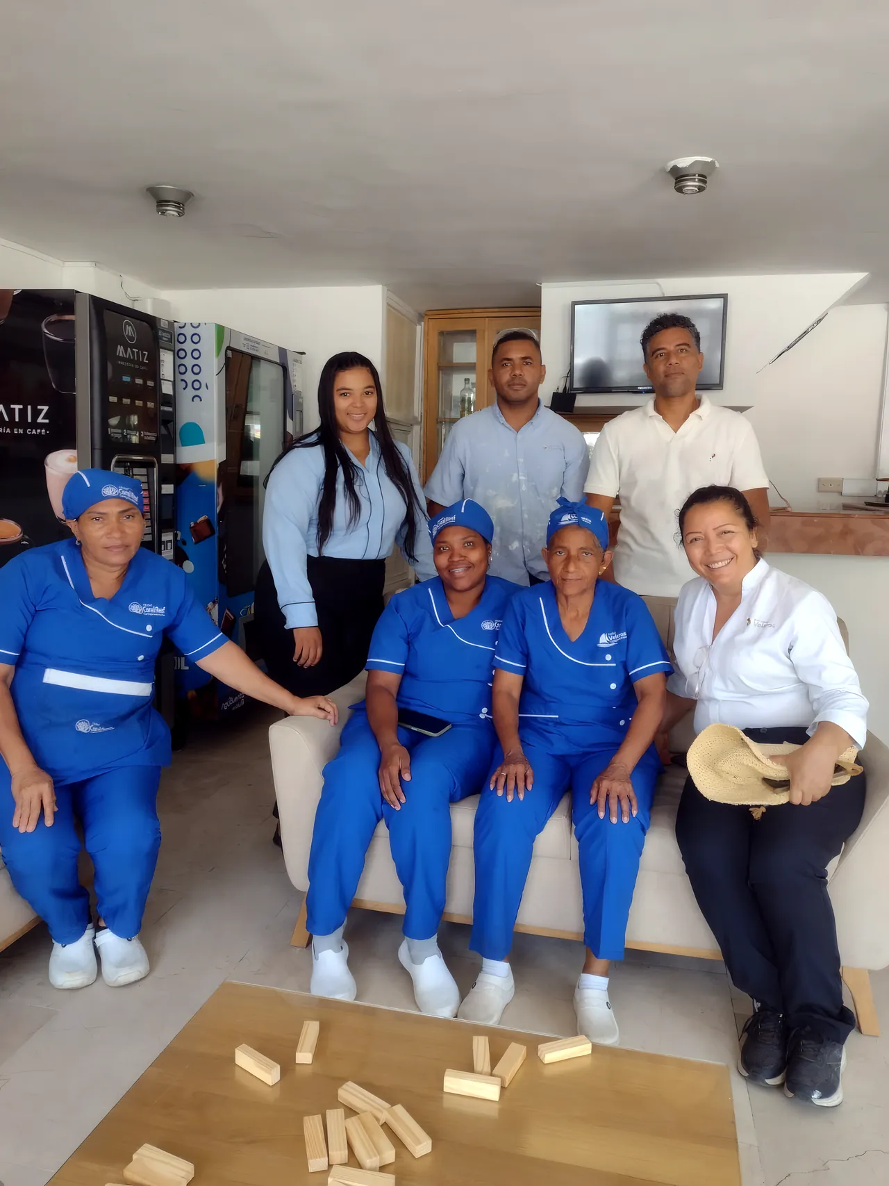 Un equipo de trabajo con uniformes azules sentado en un sofá, con bloques de madera en la mesa