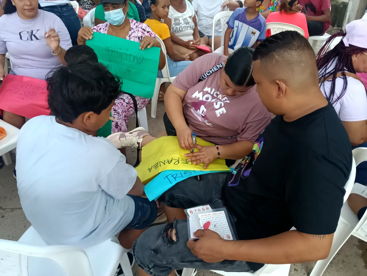 Familias pintan carteles de colores; en uno se lee «Esperanza»
