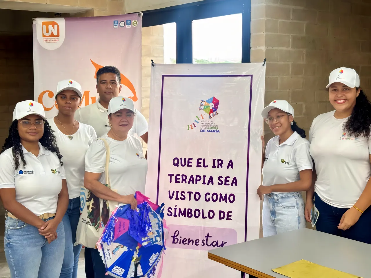 Un equipo con gorras y camisetas blancas junto a un pendón: «Que el ir a terapia sea visto como símbolo de bienestar»